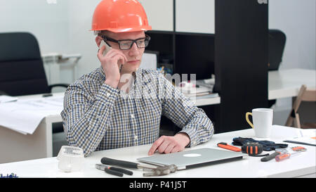 Young architect in helmet having important phone call Stock Photo