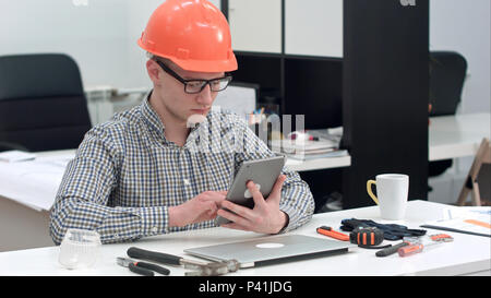 Architect with safety helmet using electronic tablet in the office Stock Photo