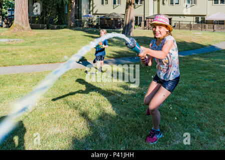 Keeping cool, summer fun,. Kids have friendly backyard water fight. Stock Photo