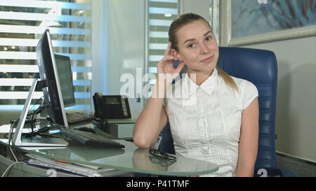Portrait of woman sitting in busy creative office looking at camera Stock Photo