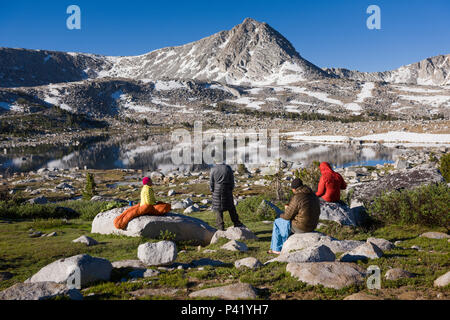 Backpackers drink coffee at sunrise at L Lake in the High Sierra mountains over Pine Creek Pass west of Bishop, California, July 2016.
