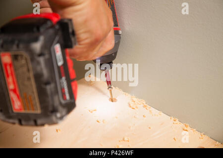 A construction worker using a battery operated drill to install screws into wood in Ontario, Canada. Stock Photo