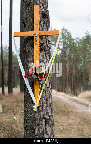 Holy cross at a dirt road in the forest. A forested sandy path leading through a pine forest. Season of the summer. Stock Photo