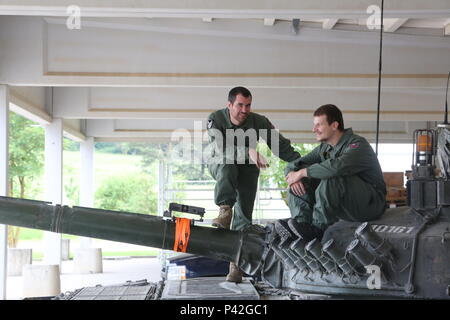 Slovenian soldiers of 45th Center for Tracked Combat Vehicles (CGBV) wait for an inspection of the Multiple Integrated Laser Engagement Systems (MILES) installed on an M-84 main battle tank during Swift Response 16 training exercise at the Hohenfels Training Area, a part of the Joint Multinational Readiness Center, in Hohenfels, Germany, Jun. 8, 2016. Exercise Swift Response is one of the premier military crisis response training events for multi-national airborne forces in the world. The exercise is designed to enhance the readiness of the combat core of the U.S. Global Response Force – curre Stock Photo