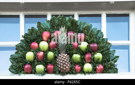 Christmas wreath decoration made of fruit, including red and green apples and one central pineapple. Colonial Williamsburg annual competition display. Stock Photo