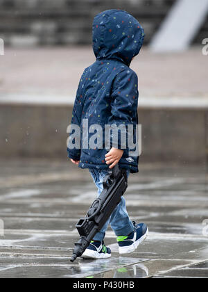 Yekaterinburg, Russia. 20th June, 2018. Fußball, WM: A little boy pulls a toy machine pistol behind him. Credit: Marius Becker/dpa/Alamy Live News Stock Photo