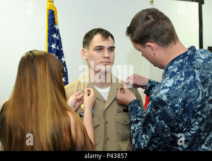 MISAWA, Japan (June 8, 2016) Master-at-Arms 1st Class Sean O'Barto, assigned to Naval Air Facility (NAF) Misawa, Japan, from Latrobe, Pa., has his collar devices pinned on by his wife, Anna O'Barto, and Master-at-Arms 1st Class Adam Baxter during a frocking ceremony at NAF Misawa. O'Barto was advanced to the rank of 1st Class Petty Officer. (U.S. Navy photo by Senior Chief Mass Communication Specialist Ryan C. Delcore) Stock Photo