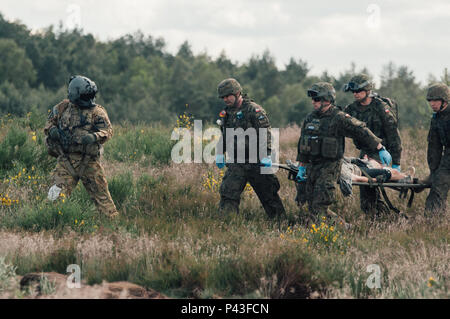 Polish medics carry an injured soldier on a litter as part of a simulated mass casualty evacuation drill during Exercise Anakonda 2016 (AN16) at Miroslawiec Air Base, Poland, June 11, 2016. AN16 a Polish-led, multinational training event running from June 7-17, involves approximately 31,000 participants from more than 20 nations and is a premier training event for U.S. Army Europe. Stock Photo