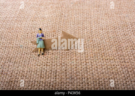 Figurine woman led by an arrow on canvas background Stock Photo