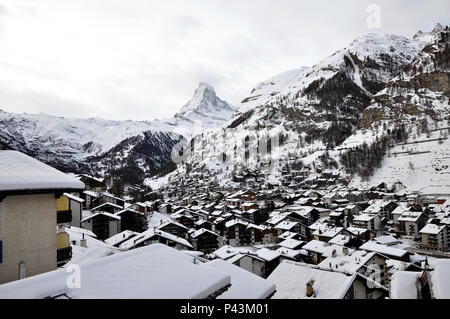 The iconic pyramid-shaped Matterhorn Peak in Zermatt, Switzerland framed by a sea of rooftops from the village below. Stock Photo