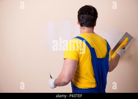 Young contractor employee applying plaster on wall Stock Photo