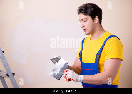 Young contractor employee applying plaster on wall Stock Photo