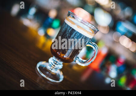 Irish coffee on irish pub bar desk. Concept of St Patrick's holiday. Holiday background. Irish national day. Warm and dark tone. Blur Background Stock Photo