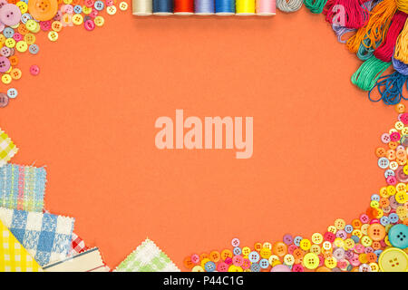 Arts and Crafts background with material and buttons on an orange textured paper background with blank copy space. Stock Photo