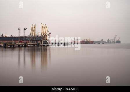 Container ship docked in the port of Amsterdam being unloaded by huge cranes on the shore Stock Photo