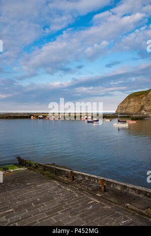 Small boats in the harbour at Staithes, North Yorkshire, North East England. A peaceful evening in May in this well known coastal village. Stock Photo