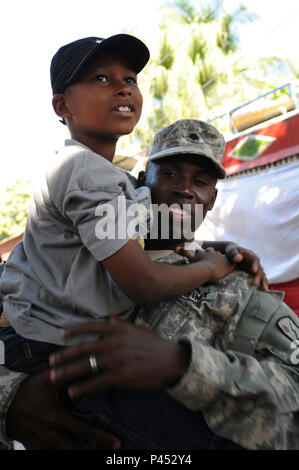 U.S. Army Cpl. Robinson Cadeus, of the 45th Sustainment Brigade out of Schofield Barracks, Hawaii, holds his nine-year-old son in Delmas, Haiti, Jan. 31, 2010. The boy is a survivor of the 7.0-magnitude earthquake that struck Haiti Jan. 12, 2010. The Department of Defense and the U.S. Agency for International Development are in Haiti supporting Operation Unified Response, a multinational, joint-service operation to provide humanitarian assistance to Haitians affected by the earthquake. Stock Photo