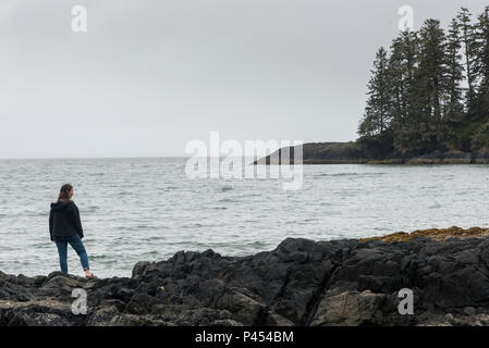 Rear view of a woman standing on the rocky shoreline, Schooner Cove Trail, Pacific Rim National Park Reserve, Vancouver Island, British Columbia, Cana Stock Photo