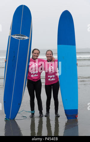 Female friends standing on the beach with surfboards, Cox Bay Beach, Pacific Rim National Park, Vancouver Island, British Columbia, Canada Stock Photo