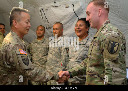 Brig. Gen. Stephen K. Curda (left), Commander, 9th Mission Support Command, shakes hands with Sgt. William J. Johnson, human resources sergeant, 303rd Maneuver Enhancement Brigade, during a visit to the Army Logistics Operations Center at exercise Imua Dawn 2016, Sagamihara, Japan, June 18, 2016.  Imua Dawn 2016 focuses on maneuver support operations and enhancing cooperative capabilities in mobility, Humanitarian Assistance and Disaster Relief (HADR), Noncombatant Evacuation Operations (NEO), and sustainment support in the event of natural disasters and other crises that threaten public safet Stock Photo