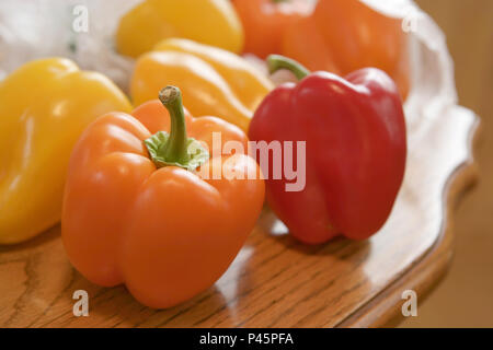 Red, yellow and orange sweet peppers on oak table Stock Photo
