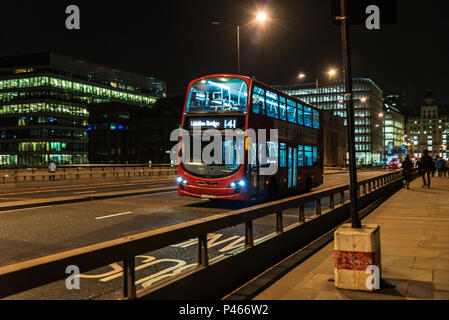London, England UK  - December 30, 2018: Bus circulating on a bridge at night with people around in London, England UK