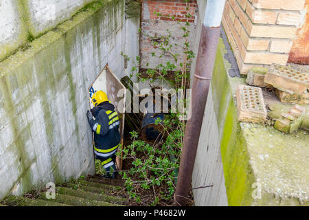 View from behind on firefighter in uniform is going down the staircase. Stock Photo