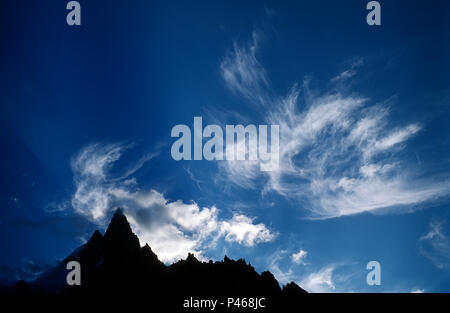 Alpine peaks silhouetted against high altitude clouds Stock Photo
