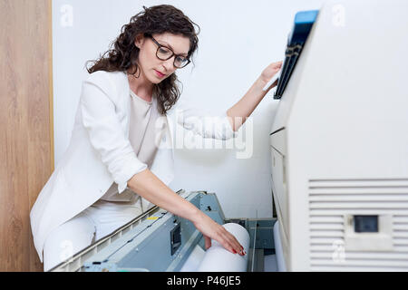 Woman putting paper into printer Stock Photo