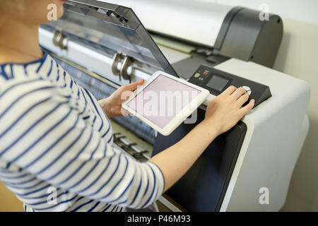 Faceless woman setting printer with tablet Stock Photo