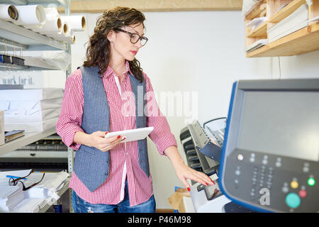 Woman calibrating printer in office Stock Photo