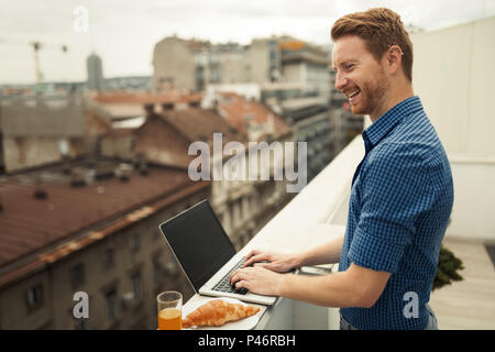 Male working on laptop on building rooftop Stock Photo