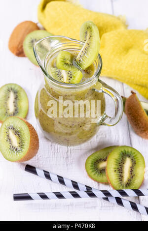 Healthy fresh kiwi smoothie in glass on a wooden background. Focus on kiwi slice in a carafe. Stock Photo