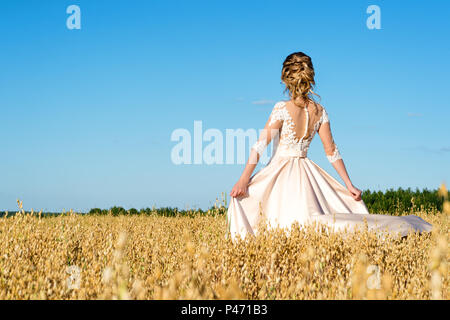 beautiful girl in beige dress in field rye, back view Stock Photo