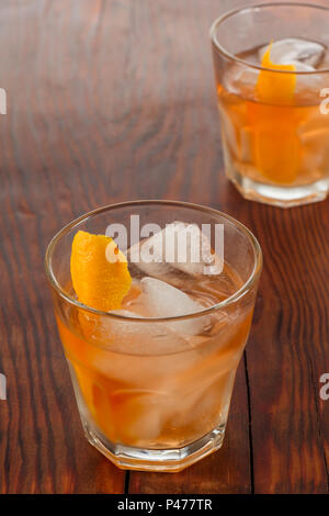 Closeup glass of negroni cocktail decorated with citrus on dark wooden background. Stock Photo