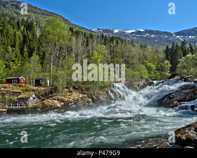 Norway, near  fjords, near Hellesylt, river with strong flow and powerful multiple waterfalls, light green Spring, snow on the tops of the mountings Stock Photo