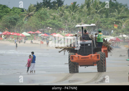 cleaning up trash in Kuta Beach, Bali Indonesia. Kuta is one of the most popular beaches in the world. Stock Photo