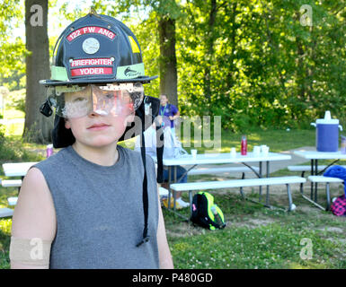 The 122nd Fighter Wing Fire Squadron presented a safety briefing to the children at Camp Red Cedar June 29, 2016 in Fort Wayne, In. The young camper pictured had been agitated the entire briefing but was instantly calmed by the weight of the fire helmut. Camp Red Cedar is a camp for children and young adults living with autism. (U.S. Air National Guard photo by SSgt Rana Franklin/released) Stock Photo
