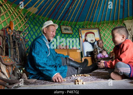 Father and son play game with animal bones inside their summertime yurt, Zhenglanqi Wuyi, Inner Mongolia Stock Photo