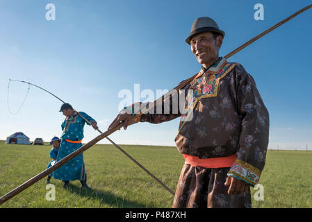 Uurga Horsemen dressed in traditional costume holds rope and pole urga or ...