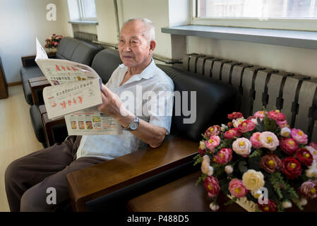 Retired man reads daily newspaper at Xin Wai Bei community center Beijing, China Stock Photo