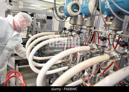 worker in sterile protective clothing in a clean room of a pharamzie company operates the technical plant for the production of drugs Stock Photo