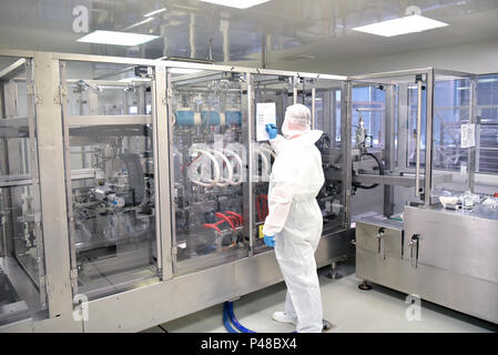 worker in sterile protective clothing in a clean room of a pharamzie company operates the technical plant for the production of drugs Stock Photo