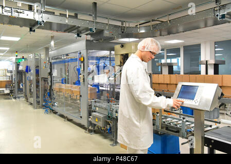 Conveyor belt worker operates a robot that transports insulin bags - modern factory for the production of medicines in the healthcare sector Stock Photo