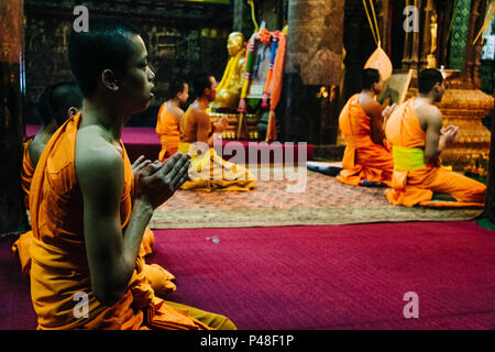 Luang Prabang or Louangphabang, Laos, Southeast Asia : Laotian Buddhist monks pray inside Wat Mai Suwannaphumaham, or Wat Mai, built in 1750 and the l Stock Photo