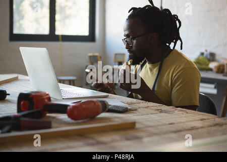 Carpenter eating sandwich while using mobile phone Stock Photo
