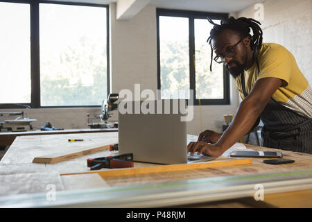 Carpenter using laptop at table Stock Photo