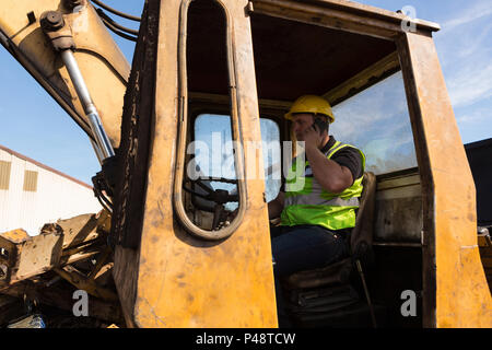 Worker talking on the phone while operating the crane Stock Photo