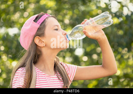 Thirsty child girl drinking water in a park Stock Photo