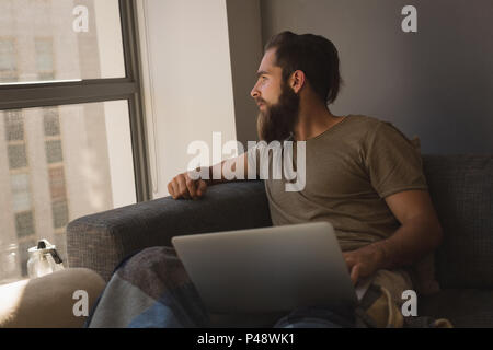 Man looking through window while using laptop Stock Photo